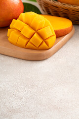 Fresh slice cut juicy mango on gray table background with leaf.
