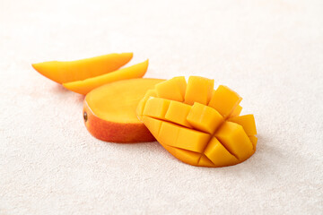 Fresh slice cut juicy mango on gray table background with leaf.