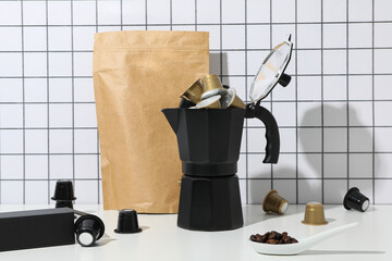 Coffee capsules, coffee maker and paper bag on light background