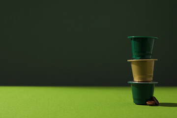 Green coffee capsules on green background, space for text