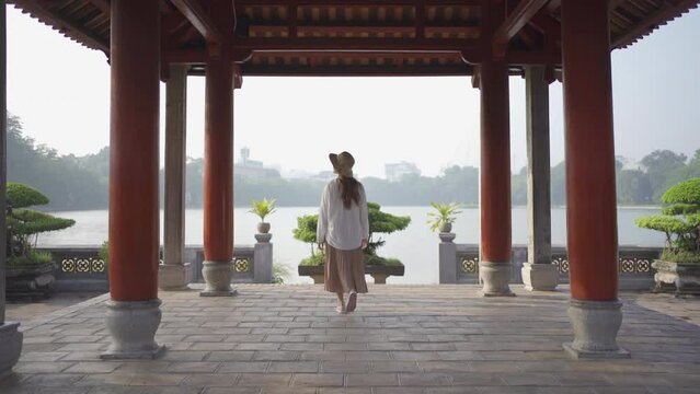 Portrait of Asian Vietnamese woman travel in The Red Bridge in public park garden with trees in Hoan Kiem Lake in Downtown Hanoi. Urban city, Vietnam..