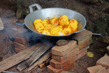 Cook sauteed corn, on a wood-burning stove.