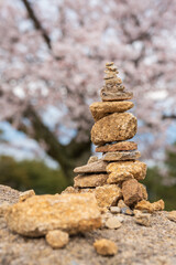 Balancing stones with cherry blossoms in springtime in Miyajima Island. Stack of stones, Pile of rocks, stones tower. Spirit of Zen. Hiroshima, Japan. 