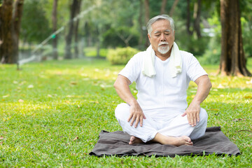 Obraz premium asian senior man meditating and doing yoga in the park