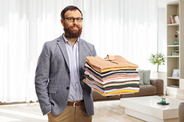 Man with a pile of folded clothes at home