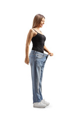 Happy young woman celebrating weight loss and trying on an old pair of jeans