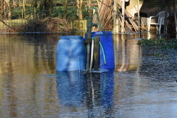 pump and water barrels in the high water of the vegetable gardens that is frozen