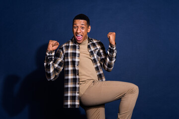 Photo portrait of nice young man celebrate raise fists winning wear trendy plaid outfit isolated on...