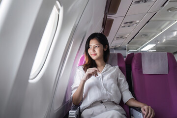 Fototapeta premium Businesswoman smiling while sitting in airplane seat. Concept of business travel and professional journey
