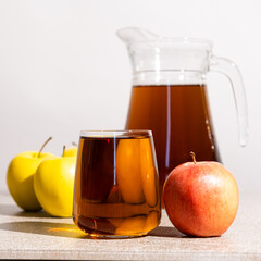 Apple juice in a glass and jug on a white background