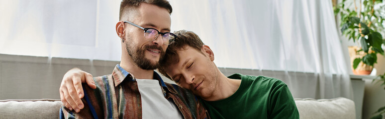 Two men, a gay creative couple, sit closely discussing trendy attire in a designer workshop.