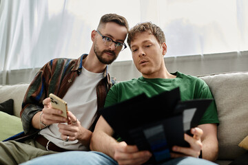 Two men sit comfortably on a luxurious couch in a designer workshop, brainstorming and creating trendy attire.