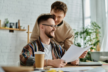 Two men sitting at table, examining paper, discussing designs for trendy attire.