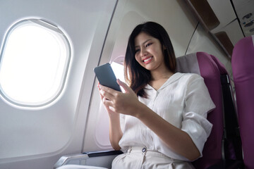 Businesswoman using smartphone in airplane seat. Concept of business travel and digital connectivity