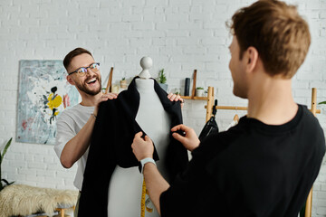 A man and mannequin hold a black shirt, working in a designer workshop.