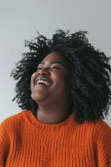 Obraz premium A woman wearing an orange sweater laughing joyfully