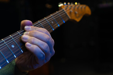 Close-up of a man's hand on the neck of a guitar. Man plays an electronic guitar in close-up