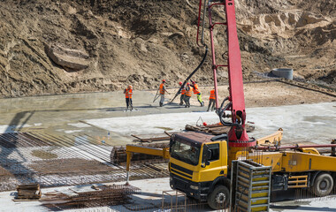 Foundation construction, workers pouring concrete at construction site