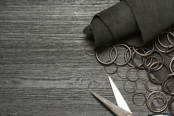 Leather piece and metal rings furniture on the wooden black table background. Leather craft...