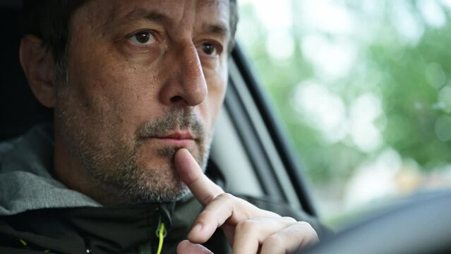 Portrait of concerned male driver thinking with index finger on lips in a car