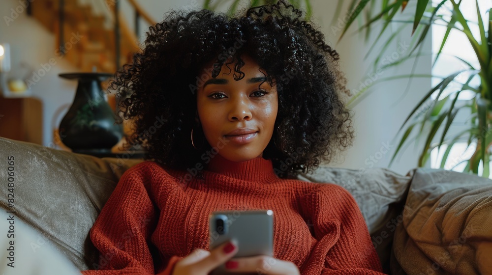 Wall mural curly girl looks at the phone screen. Selective focus