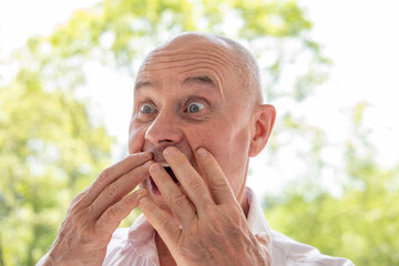 65-year-old eccentric man very surprised, senior showing grimaces, winks, mischievous grin,...