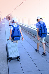 two children with suitcase, young traveler, boys of 8-10 years old with backpacks in outdoor...