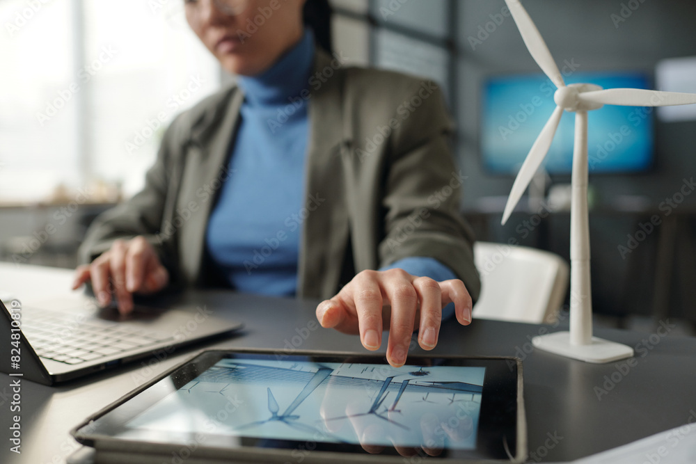 Poster hand of young female architect over screen of tablet with windmills during network and analyzing onl