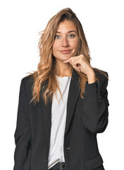 Young businesswoman in a suit smiling happy and confident, touching chin with hand.