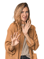 Caucasian blonde woman in studio rejecting someone showing a gesture of disgust.