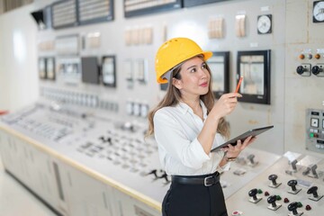 With a commitment to excellence Asian female engineer in power plant working and pointing at...