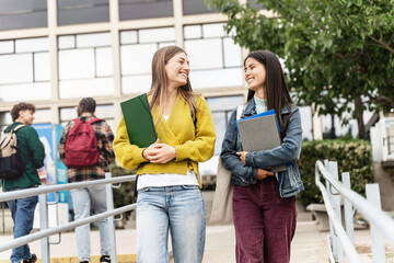 Two University Student girls walking outdoors at the college campus going out of University lecture