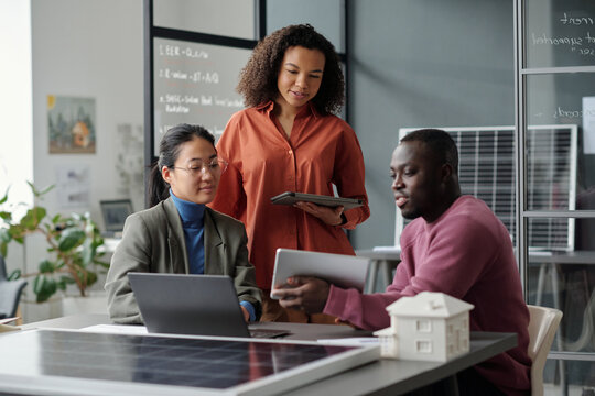 Young African American businessman with tablet making presentation of his architectural project to intercultural female colleagues