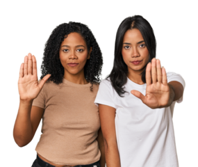 Young Latin friends in studio standing with outstretched hand showing stop sign, preventing you.