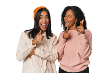 Young Latin friends together in studio pointing to front with fingers.