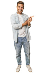 Full body portrait of a man in studio smiling cheerfully pointing with forefinger away.