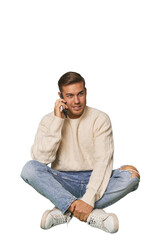 Caucasian man sitting on floor talking on the phone in a studio