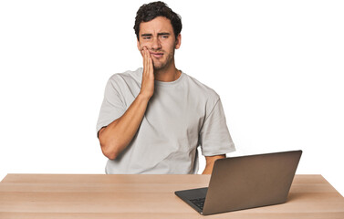 Hispanic young man working on laptop having a strong teeth pain, molar ache.