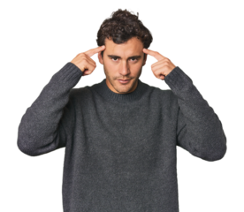 Young Hispanic man in studio focused on a task, keeping forefingers pointing head.