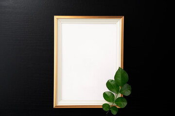 Picture frame and leaf on black wooden texture background. Work desk space