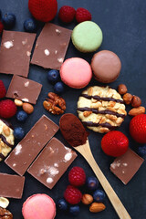 Macarons, chocolate, cookies, berries and various nuts on dark blue background. Top view.