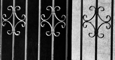 Wrought Iron Ornamented Entrance Against Sunlit Wall. A Study in Pattern and Texture. Contrast of light and shadow. Black and white. Monochrome.