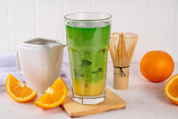 Orange matcha latte drink on white kitchen taable