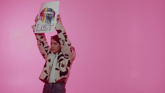 A young neutral orientation person demonstrating lgbt community placard to support their rights. Concept of tolerance. Being different. An adult woman showing rainbow colors lips with lgbt slogan