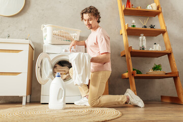 A man in cozy homewear sits in front of a washing machine.
