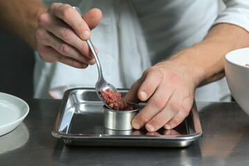 Chef's hands serving and decorating meal in restaurant kitchen