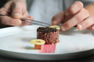 Chef's hands serving and decorating meal in restaurant kitchen