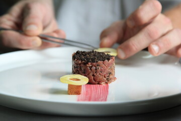 Chef's hands serving and decorating meal in restaurant kitchen