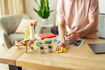 A man in cozy homewear sitting at a table cleaning near laptop.