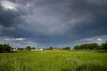 Panorama of rural landscape at wild changing stormy weather condition with rain and sun